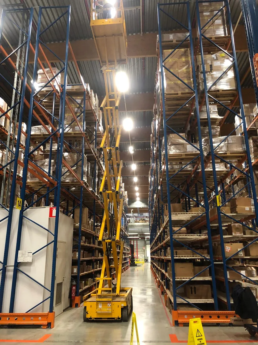 Verlichting vervangen tussen magazijnstellingen met de hoogwerker