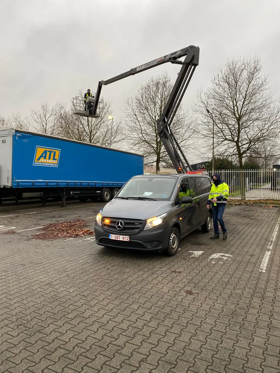 Onze bestelwagen en hoogwerker op een parking